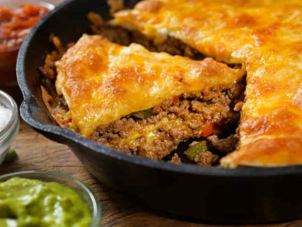 Taco Pie: A Tasty Twist on a Classic Favorite 5 Sliced taco pie in a skillet served with salsa, sour cream, and guacamole