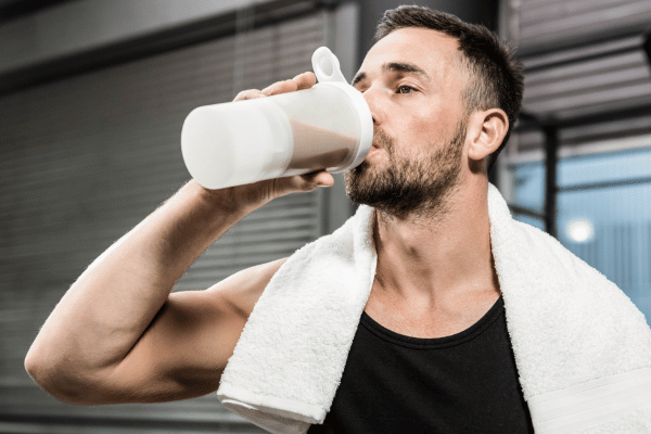 How Low Carb Protein Shakes Can Boost Your Fitness Goals 3 A man is drinking a low carb protein shake from a tumbler.