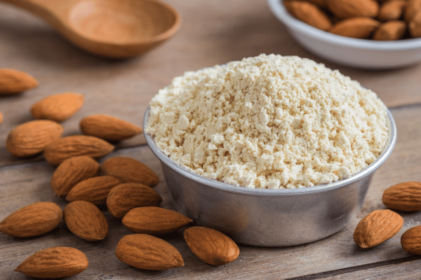 Carb Free Bread Recipe: A Simple Guide for Beginners 18 Almond flour fills a cup, surrounded by scattered whole almonds.
