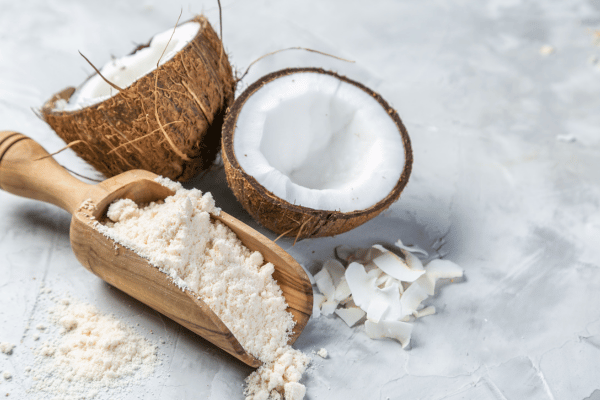 Carb Free Bread Recipe: A Simple Guide for Beginners 19 Coconut flour rests in a scoop beside a coconut sliced in half.
