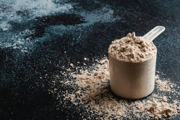 How Low Carb Protein Shakes Can Boost Your Fitness Goals 4 A measuring cup is filled with protein shake powder.