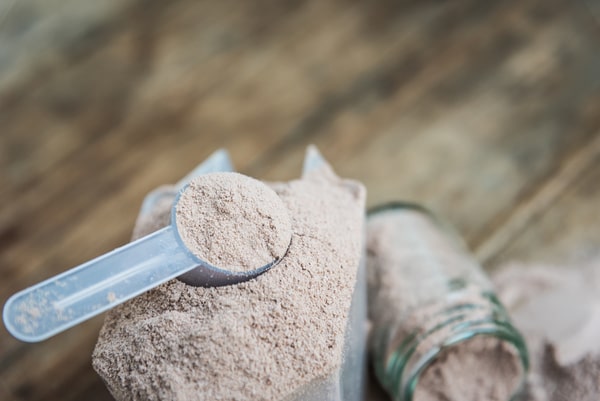 Keto CVS Essentials: Must-Have Products for Your Diet 5 A scoop of chocolate BHB powder resting on top of an open bag, with a spilled glass jar of powder in the background
