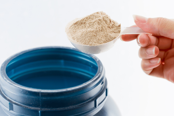 How Low Carb Protein Shakes Can Boost Your Fitness Goals 6
A cup is being filled with protein shake powder from its container.