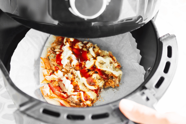 Totino's Pizza Air Fryer Style - Perfectly Crispy and Easy 6 Opening an air fryer to reveal a hot, freshly cooked pizza inside, ready to be served.
