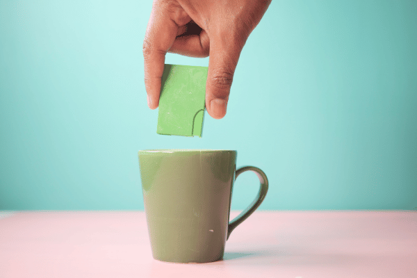 Pyure Keto Recipes: How to Satisfy Your Sweet Tooth 7 A young man is sitting at a table, holding a cup of tea in one hand.