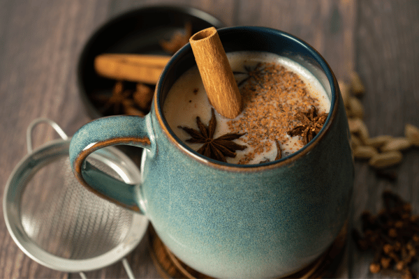 Dutch Bros Chai Drinks vs Competitors: Who Wins? 11 A warm beverage in a blue mug with star anise, cinnamon, and spices, likely chai tea or spiced latte.