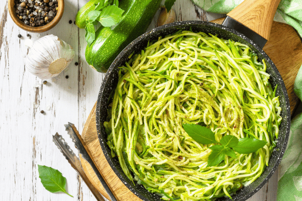 The Best Keto Pasta to Satisfy Your Carb Cravings 2 A top view of a fresh best keto pasta dish made from thinly sliced cucumber, arranged in long strips to look like noodles.