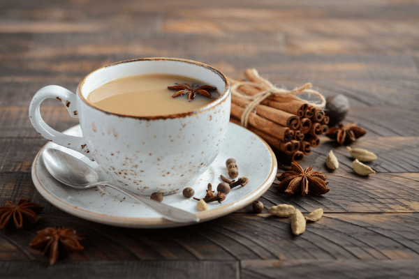 Dutch Bros Chai Drinks vs Competitors: Who Wins? 3 A hot cup of chai in a white cup rests on wood, with chai accessories beside it.