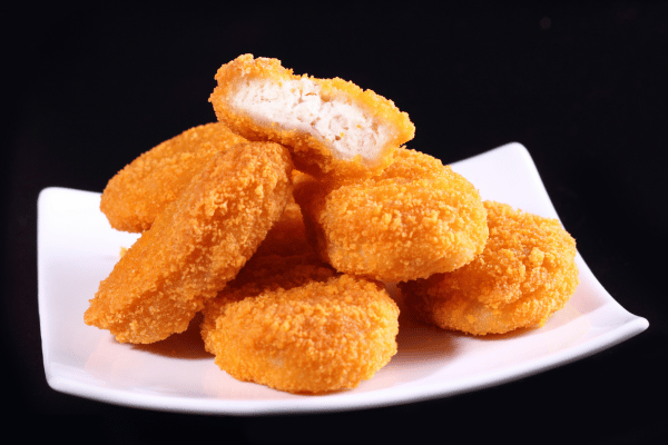 Chicken McNuggets Carbs: A Guide for Low-Carb Dieters 4 A white plate overflowing with golden Chicken McNuggets, beautifully contrasted against a sleek black background.