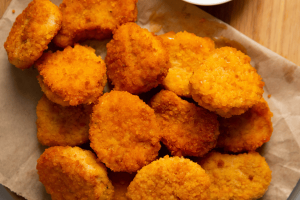 Chicken McNuggets Carbs: A Guide for Low-Carb Dieters 6 A batch of freshly made chicken nuggets nestled in parchment paper, highlighting their delicious crunch and warm, inviting appearance.