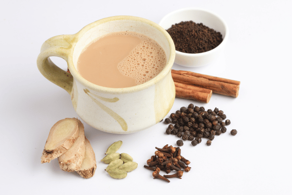 Dutch Bros Chai Drinks vs Competitors: Who Wins? 7 A chai latte in a greenish-white cup, surrounded by aromatic spices.