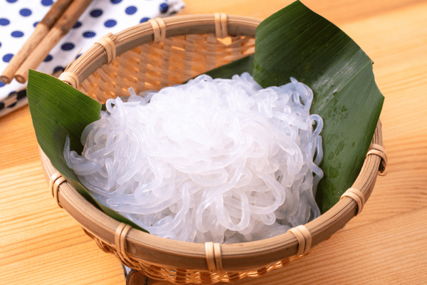 The Best Keto Pasta to Satisfy Your Carb Cravings 5 A rustic brown wooden basket lined with vibrant green banana leaves holds a generous portion of shirataki noodles-the best keto pasta.