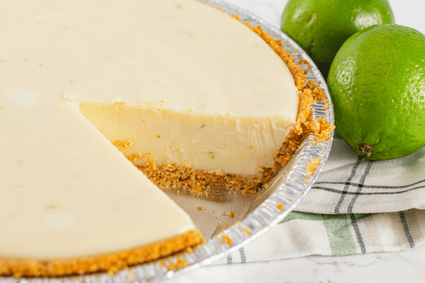 A creamy cheesecake with a golden keto graham cracker crust, sliced to reveal its smooth texture and firm base.