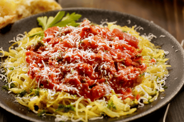 The Best Keto Pasta to Satisfy Your Carb Cravings 7 A beautifully arranged square of spaghetti, neatly placed on a plate, topped with a rich, savory sauce and a generous sprinkle of melted cheese.