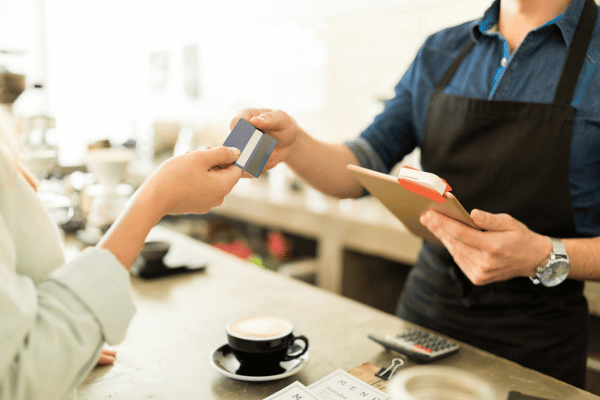 Dutch Bros Chai Drinks vs Competitors: Who Wins? 10 A customer hands their card to the barista to pay for a drink in a black cup.