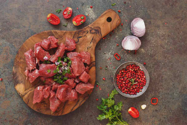 Keto Beef Stew Recipe: Low-Carb Comfort in a Bowl 4 Raw chopped beef on a wooden board with tomatoes and red onions