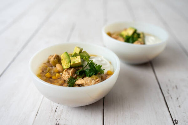 Easy Keto White Chicken Chili Recipe for Cozy Nights 2 Bowls of white bean chicken chili with sour cream and avocado slices