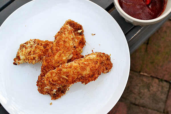 How to Cook Chicken Tenderloins: Easy and Tasty Recipe 3 Breaded and baked chicken tenders on a plate with a side of tomato sauce