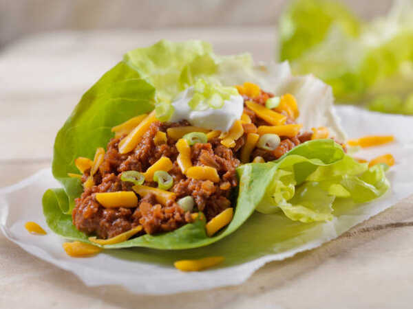 Easy Keto Chili Recipe for a Hearty, Low-Carb Meal 9 Homemade chili in lettuce wrap topped with sour cream, shredded cheese, and chopped green onions