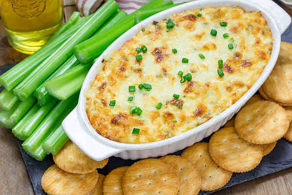 Baked crab dip served with celery sticks and crackers