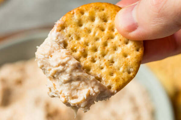 A cracker dipped into cold crab dip