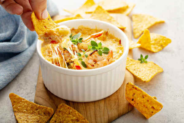 Chips dipped into a spicy seafood dip in a ramekin