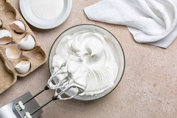 Whipping egg whites with sugar in a bowl to make meringue