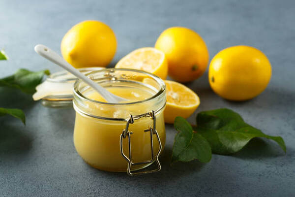 Homemade lemon curd in a jar with fresh lemons