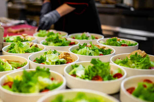 Keto Caesar Dressing That's Creamy, Tangy, and Easy 4 A chef preparing Caesar salad in bowls