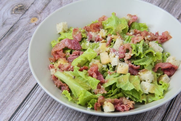 10 Low Carb Salads Perfect for Summer Picnics 5 A low-carb salad with fresh lettuce, crispy bacon, croutons, and grated cheese served in a white bowl on a wooden table
