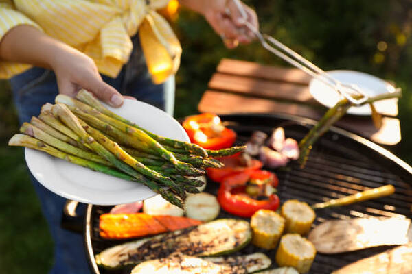 10 Low-Carb BBQ Sides Perfect for Your Next Grill Party 13 A woman cooking vegetables on a barbecue grill outdoors
