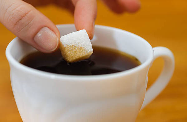 Understanding Iced Tea vs Sweet Tea: Key Differences 5 Mixing a sugar cube into a hot cup of black tea