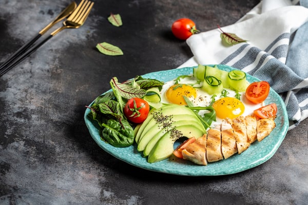 16 Tasty Keto Brunch Ideas: Sweet and Savory Combos 3 A simple keto brunch plate with grilled chicken, eggs, avocado slices, spinach, cucumber, and cherry tomatoes
