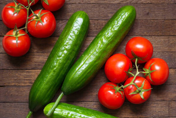 Easy Keto Cucumber Tomato Salad for Fresh Summer Flavor 5 Red ripe tomatoes and big green cucumbers on wooden background