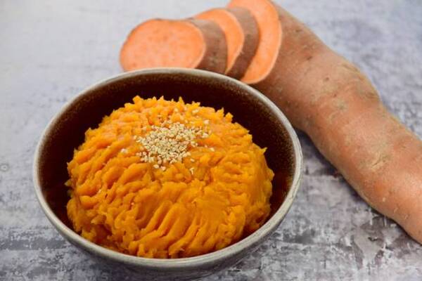 Delicious Keto Sweet Potato Casserole for Holiday Feasts 4 Sliced sweet potato with a bowl of mashed sweet potatoes sprinkled with sesame seeds