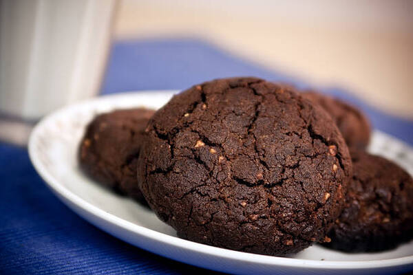 Keto No-Bake Cookies: 5 Variations for Every Craving 4 A bunch of home-made chocolate peanut butter cookies on a plate, with a glass of milk in the background