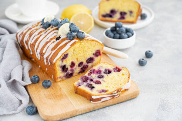 Easy Keto Lemon Blueberry Bread Recipe for a Sweet Treat 2 Lemon blueberry loaf with lemon icing and fresh berries on a wooden board