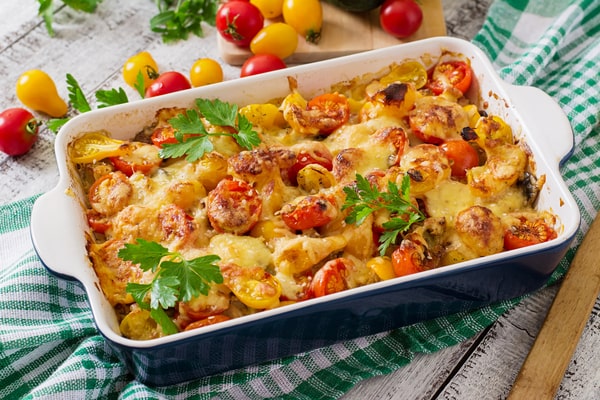 Cauliflower Bake: Deliciously Cheesy and Healthy Recipe 11 A vegetable casserole with zucchini, mushrooms, and cherry tomatoes, topped with melted cheese and fresh parsley, served in a blue baking dish