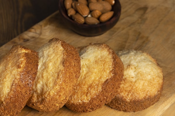 Keto English Muffin Recipe for Quick Breakfasts 3 Four keto muffins are neatly lined up on a wooden board, served with a small cup of almonds