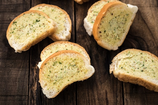 Frozen Garlic Bread in Air Fryer: Ready in 5 Minutes! 3 Slices of garlic bread with herbs, arranged on a wooden surface