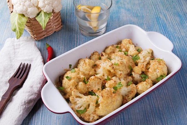 Cauliflower Bake: Deliciously Cheesy and Healthy Recipe 3 A baked cauliflower dish with a crispy topping, garnished with fresh parsley, is served in a white baking dish