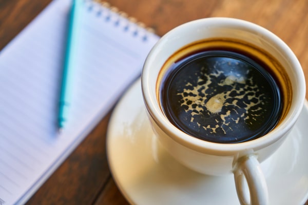 How Much Caffeine in Decaf Espresso: Brewing Insights 4 A cup of decaf espresso on a saucer beside a notepad and pen