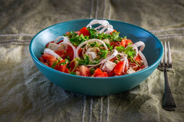 Easy Red White and Blue Salad Recipe for Your BBQ 6 A blue bowl of red white and blue salad with tomatoes, feta cheese, onions, and fresh parsley