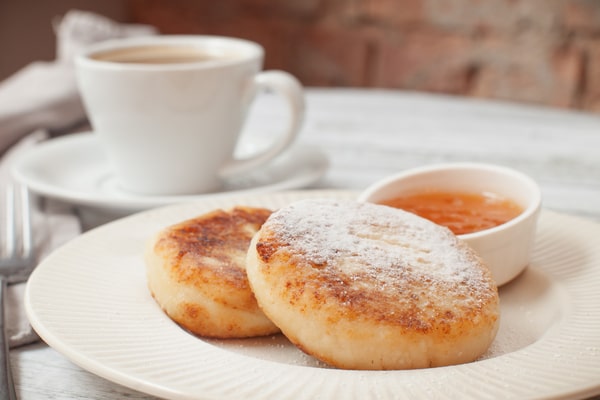 Keto English Muffin Recipe for Quick Breakfasts 7 Two keto English muffins are served on a white plate with a cup of coffee beside them