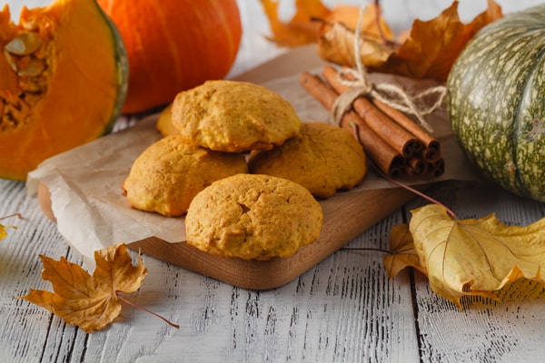 Keto Pumpkin Cookies: Perfect for Holiday Baking Ideas 7 A rustic wooden board with keto pumpkin cookies surrounded by pumpkins, cinnamon sticks, and autumn leaves