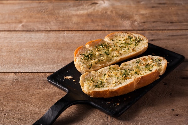 Frozen Garlic Bread in Air Fryer: Ready in 5 Minutes! 9 Two slices of garlic bread with herbs served on a black wooden board