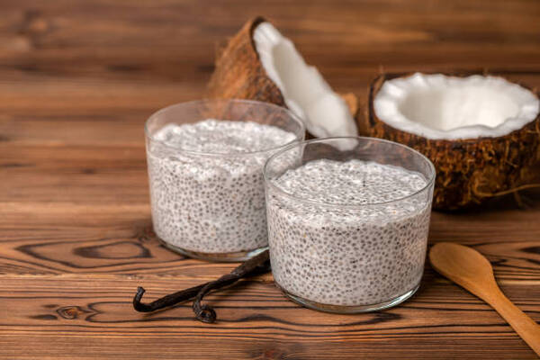Delicious Low-Carb Chia Pudding Recipe Perfect for Any Day 4 Chia pudding in glasses with vanilla pods, spoon and coconuts on wooden background