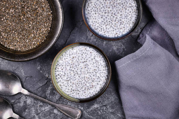 Delicious Low-Carb Chia Pudding Recipe Perfect for Any Day 2 Chia seed pudding made with dry seeds soaked in milk in small bows surrounded by spoons