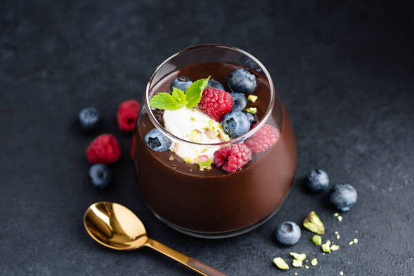 Easy Keto Chocolate Mousse Recipe for a Quick Dessert Fix 6 Dark chocolate mousse with pistachios, berries and cream in jar, black stone background