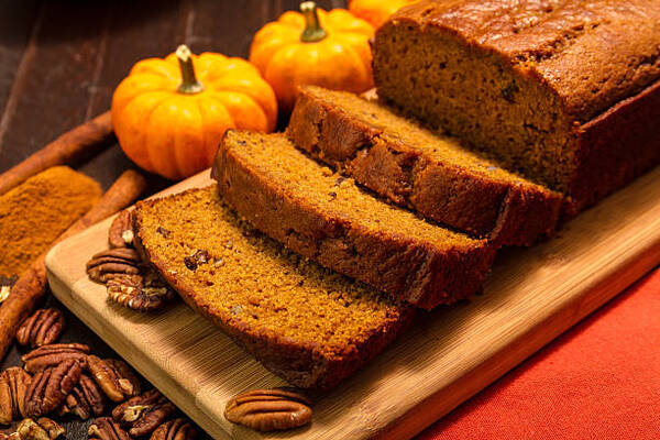 Soft and Moist Keto Pumpkin Bread You’ll Want Every Fall 2 Sliced pumpkin bread loaf on a wooden cutting board with pecan nuts and cinnamon spices